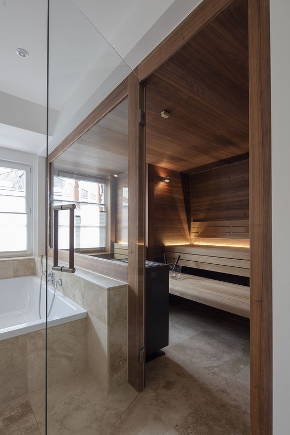 a stylish modern sauna with a glass wall, wood all over it and some intimate light for an ambience