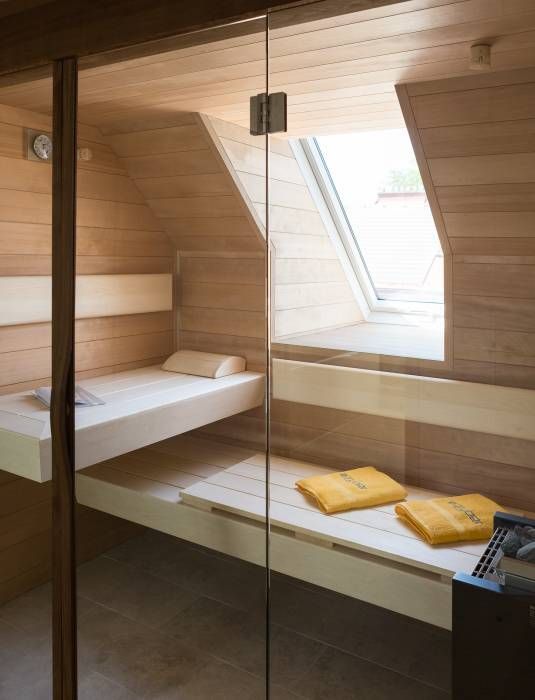 a tiny home steam room clad with light stained wood and a couple of benches plus a small window for natural light