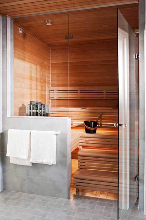 A tiny welcoming steam room clad with wood, with step benches and lights built in under the steps