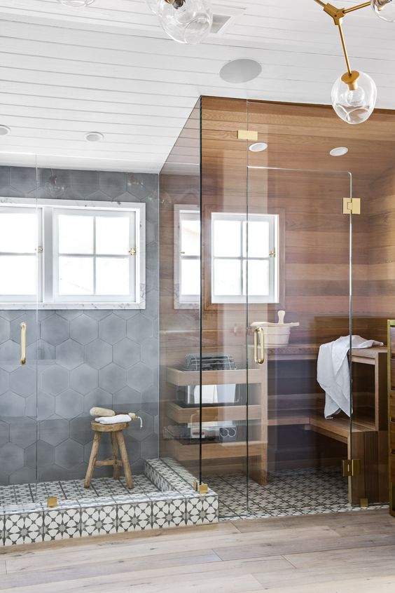 a tiny yet chic steam room covered with wood, with two benches and a window plus touches of gold
