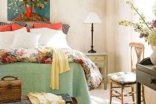 a vintage farmhouse with printed wallpaper, printed and colorful bedding, vintage furniture and a bright artwork