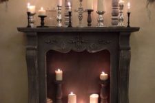 a vintage fireplace with pillar candles and vintage candle holders in the fireplace and on the mantel