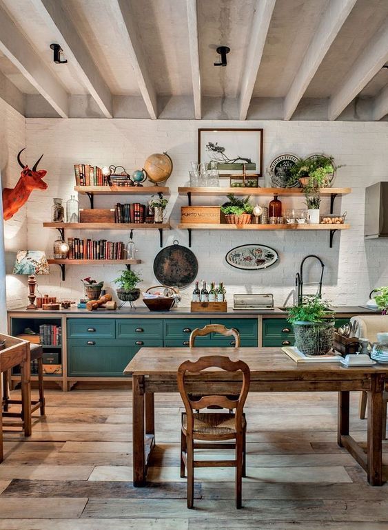 a vintage rustic kitchen with teal and stained cabinets, a stained dining set with vintage chairs, open shelves and an orange faux taxidermy piece