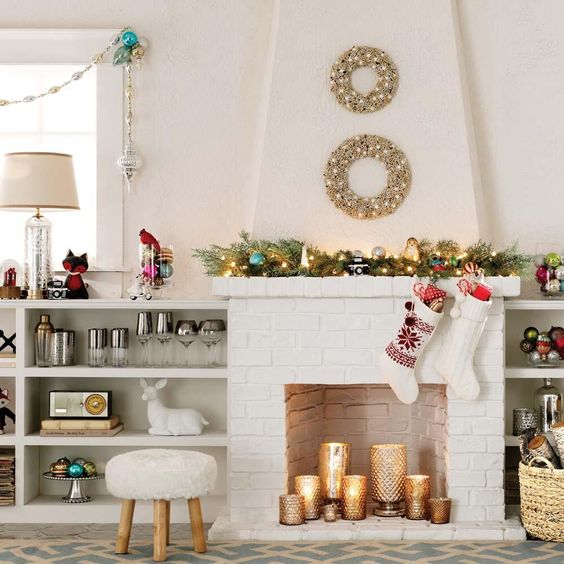 a white brick fireplace with gold mercury glass candle holders with pillar candles