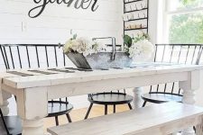 an airy and welcoming farmhouse dining room with a white dining set, black chairs, a black chandelier and much light