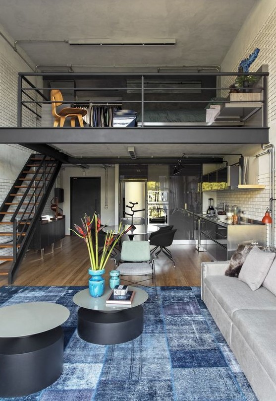 An industrial home with a loft sleeping space and closet, with a dining living room below and round tables is a stylish idea
