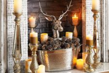 bold rustic styling with candles placed on vintage candle holders, a tub with pinecones and a fake deer head