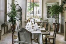 a beautiful Provence dining room with a couple of vintage buffets, a long table, vintage chairs, potted trees and lots of light