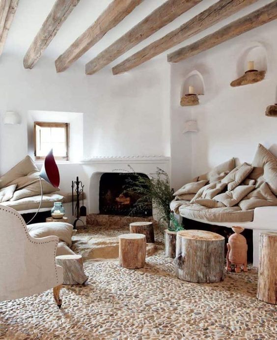 a beautiful Provence living room with neutral furniture, a fireplace, wooden beams on the ceiling and a quirky stone floor