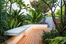 a beautiful minimalist deck with a built-in bench, potted greenery, trees and plants, with built-in lights is amazing