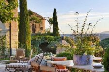 a bold Provence terrace with vintage forged furniture, a table with a stone tabletop, greenery and blooms and striped textiles