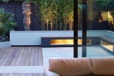 a chic minimalist terrace clad with wood and tiles, built-in lights in benches, growing trees is a stylish and cool nook to be in