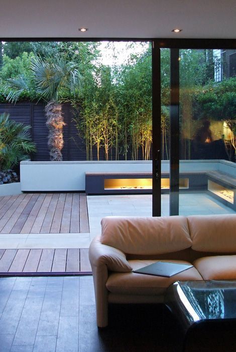 a chic minimalist terrace clad with wood and tiles, built-in lights in benches, growing trees is a stylish and cool nook to be in
