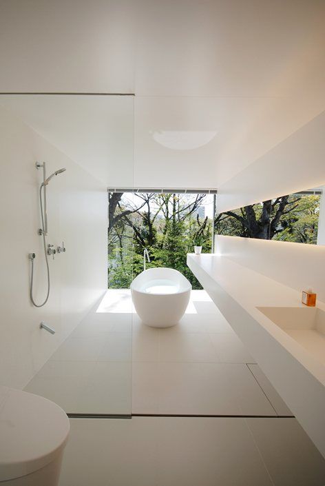 a concrete creamy bathroom with large scale tiles, a long floating vanity and a glazed wall for rainforest views