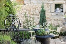 a delicate Provence terrace with black and white forged furniture, potted plants and blooms is a lovely space to spend time in