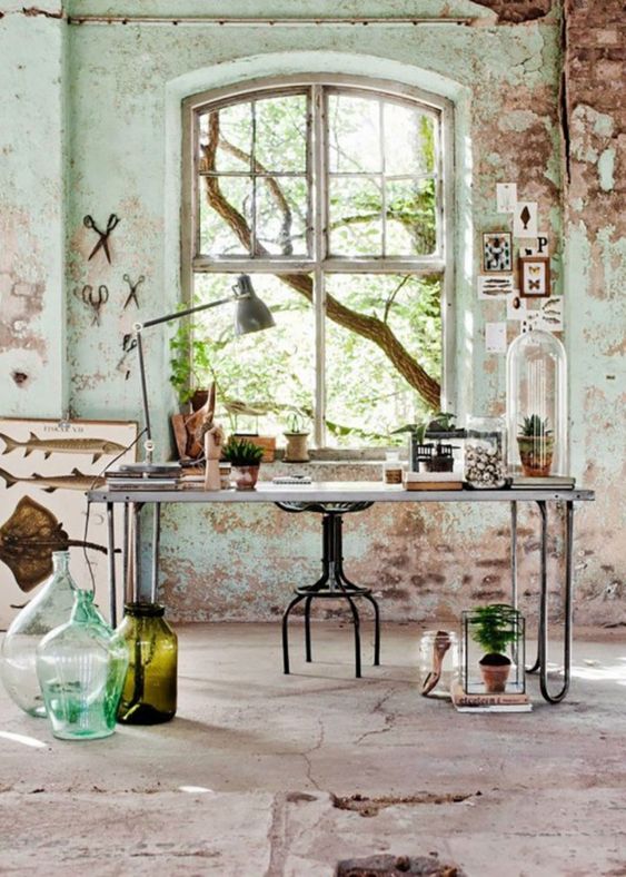 a farmhouse wabi-sabi home office with large bottles and vases, metal chairs and potted greenery and succulents