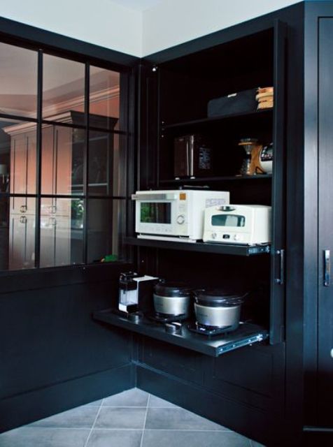 a large black cabinet holding all the appliances on retractable shelves helps to keep the kitchen in order and make it cooler