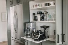 a large cabinet taken by shelves that hold mugs of all kinds and a coffee machine and other appliances is your hidden drink station