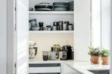 a large storage unit with folding doors, drawers and open shelves hides a lot of dishes, tableware and a coffee and tea station, additional lights make looking for the pieces easier