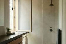 a minimalist bathroom clad with concrete, a flaoting wood and concrete vanity, a window and a wooden floor and ceiling