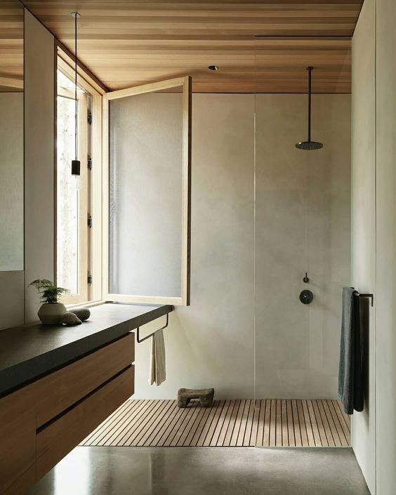 a minimalist bathroom clad with concrete, a flaoting wood and concrete vanity, a window and a wooden floor and ceiling