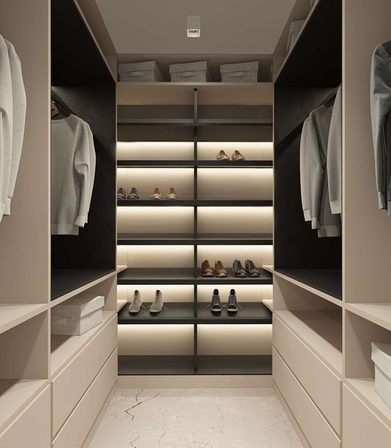 A minimalist closet done in light shades, with black shelves and much built in light plus drawers
