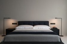 a minimalist contrasting bedroom with a black upholstered bed, a black leather bench, black nightstands and lamps