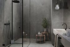 a minimalist grey stone-like tiles, a shower space clad with glass, a floating vanity with a sink and pendant lamps plus a skylight