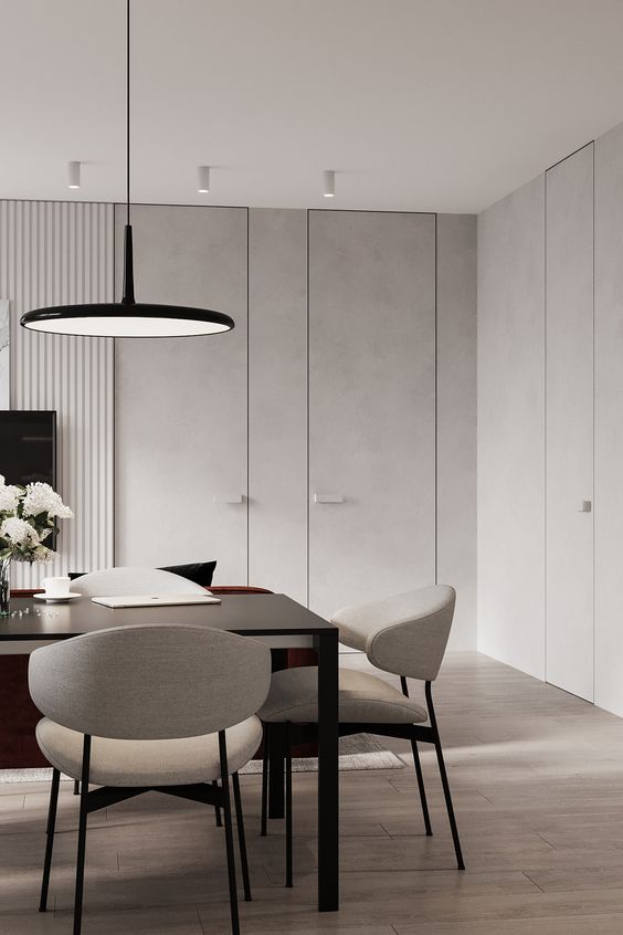 a minimalist light grey dining room with a black table, neutral chairs, a black pendant lamp is a stylish space for meals and work