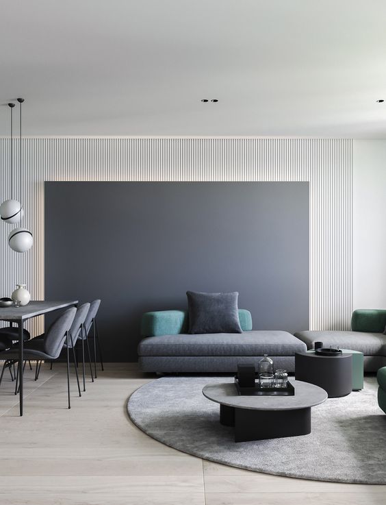 a minimalist living space with a chalkboard wall, dark coffee tables, a grey sectional sofa plus colored pillows