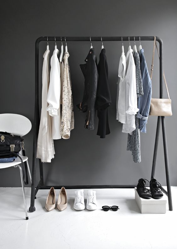 a minimalist makeshift closet done with a black frame, a white chair and a box for shoes