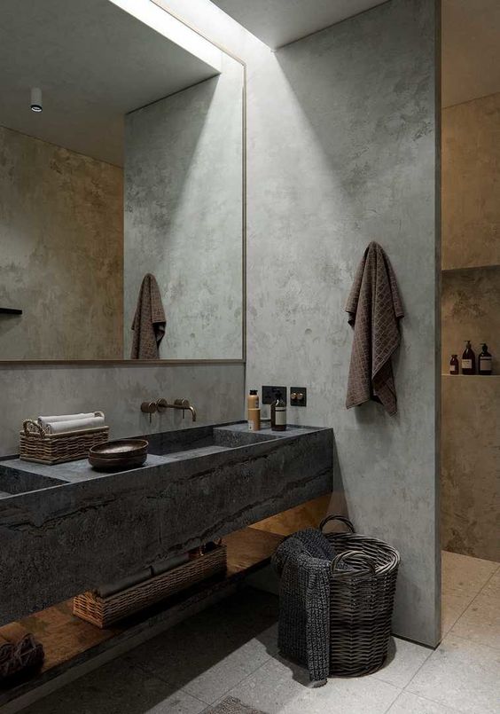 a minimalist meets wabi-sabi bathroom with concrete walls, a stone vanity and a basket for storage