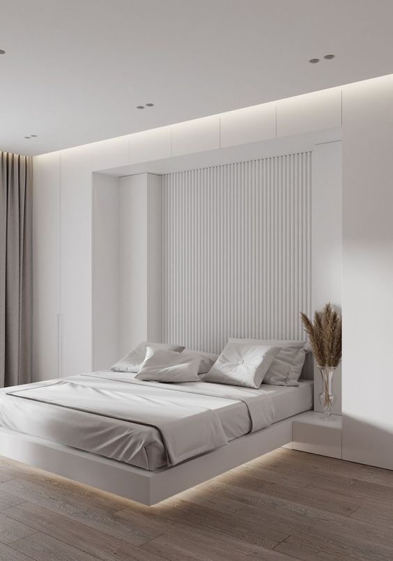 A minimalist neutral bedroom with a slab accent wall, a floating bed with lights, built in nightstands and greige curtains