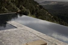a minimalist terrace with a stone deck and woven daybeds plus a long pool and a forest view is a gorgeous space and you need nothing more