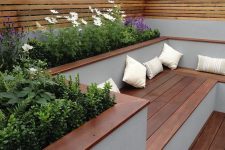 a minimalist terrace with rich-stained wood, built-in benches, potted blooms and greenery and plank wood screens around