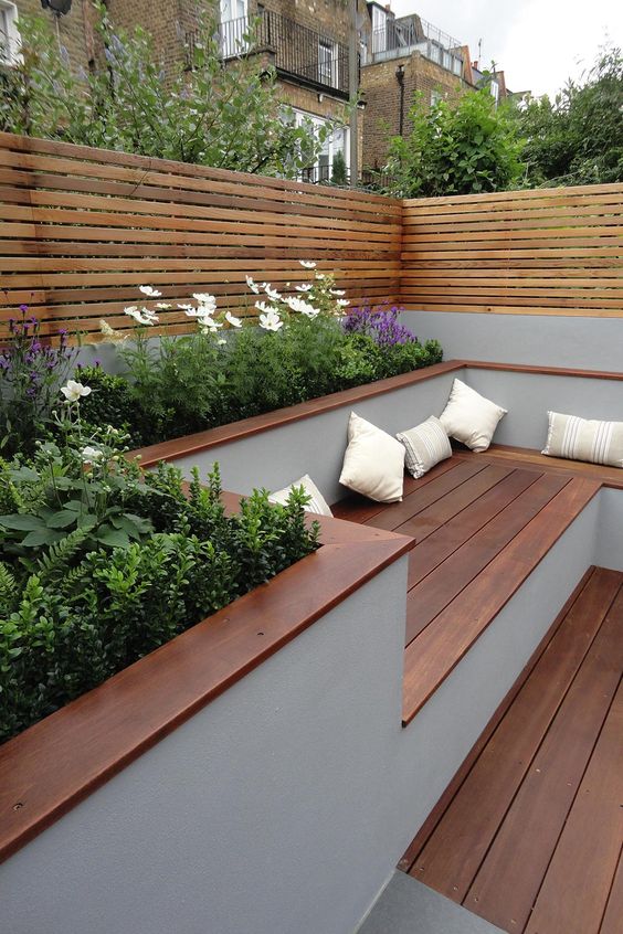 a minimalist terrace with rich-stained wood, built-in benches, potted blooms and greenery and plank wood screens around