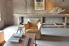 a minimalist wabi-sabi living room in neutrals with brick walls, a concrete floor and rough and brutal furniture