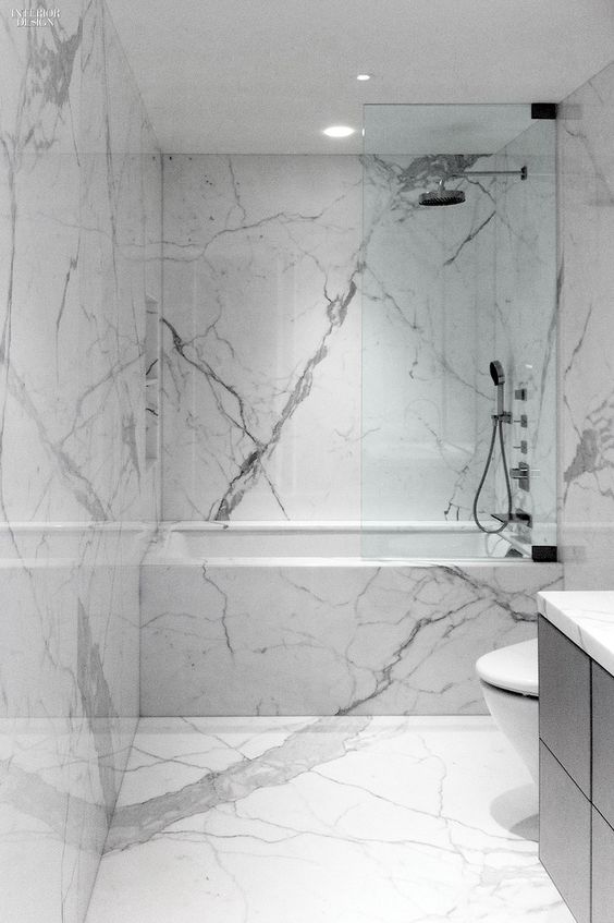 a minimalist white marble bathroom with a black vanity, white appliances and simple fixtures