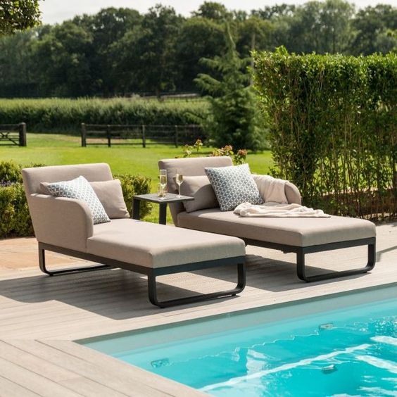 a modern lounger with metal framing and very comfy upholstery, a black and an armholder plus pillows for maximal coziness
