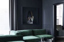 a moody graphite grey living room with a small coffeee tables, an emerald grene sectional sofa and a statement artwork