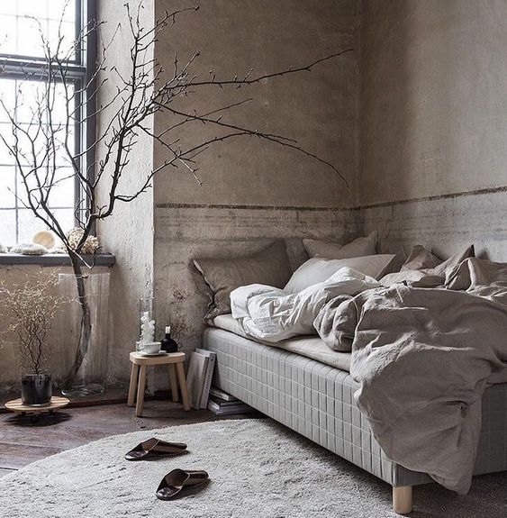 a neutral brutal interior with concrete walls, a wooden floor and some very simple yet comfortable furniture