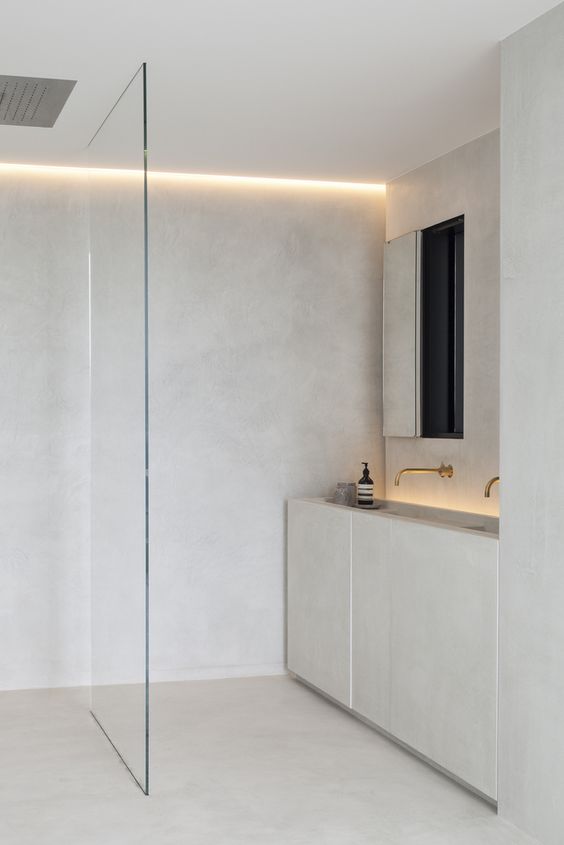 A neutral minimalist bathroom with built in lights, a shower with a glass partition and a vanity with two sinks built in