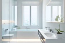 a pure white minimalist bathroom with a floating vanity, a bathtub with built-in lights, a shower clad with glass and a window