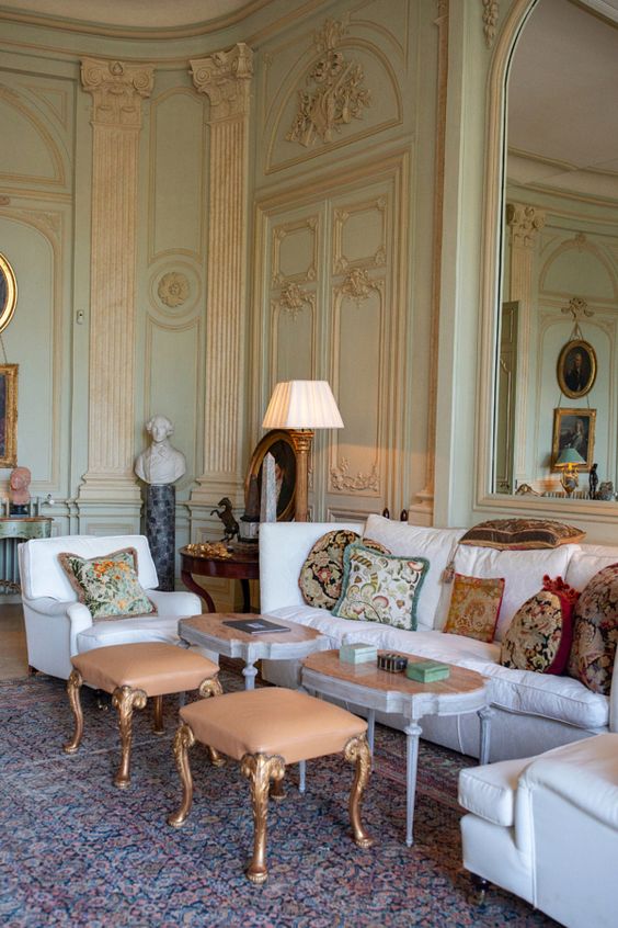 a refined Provence living room with light green and gold walls, chic and beautiful furniture, table lamps and statuettes