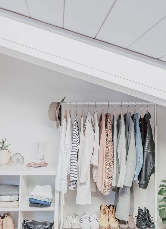 a small attic closet in white, with a makeshift closet, a shoe shelf and an open storage unit plus some plants