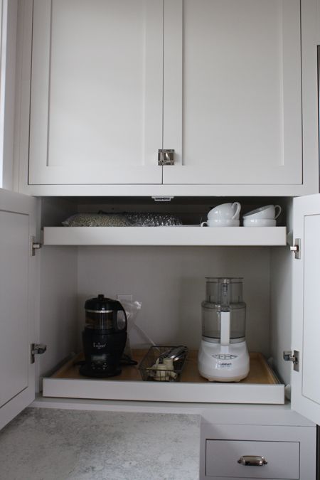 a small cabinet with retractable shelves that hold appliances and mugs is a cool idea to make your own tea and coffee station hidden