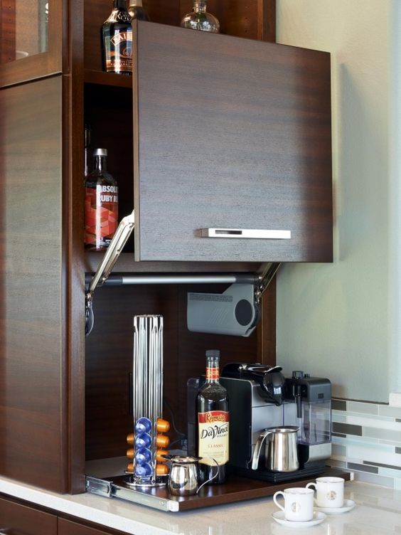a small dark stained cabinet with a sliding door and a mini coffee station inside, on a retractable shelf is a stylish idea
