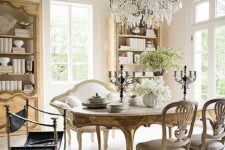 a sophisticated Provence dining space with light-stained bookcases, a vintage stained table and chairs, a creamy loveseat and a crystal chandelier