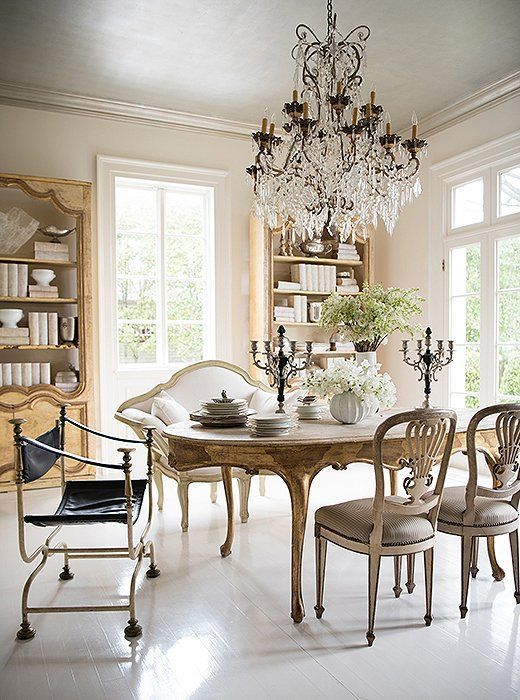 a sophisticated Provence dining space with light-stained bookcases, a vintage stained table and chairs, a creamy loveseat and a crystal chandelier