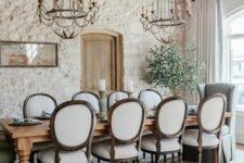 a sophisticated Provence dining space with stone walls and a wooden ceiling and beams a stained table and vintage chairs vintage chandeliers